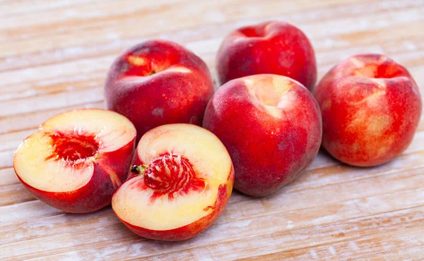 Seluruh dan setengah buah persik merah segar di meja kayu. — Stok Foto