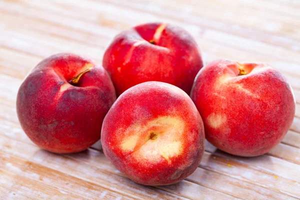 Pêches rouges entières et demi fraîches sur table en bois. — Photo