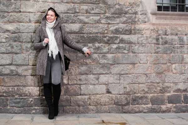 Chica en la capucha de pie cerca de pared de piedra —  Fotos de Stock