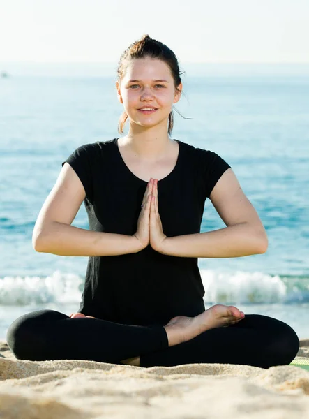Siyah tişörtlü kadın oturuyor ve yoga yapıyor. — Stok fotoğraf