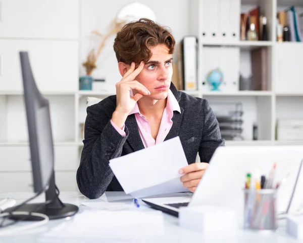 Attraktiver, nachdenklicher junger Mann, der mit Dokumenten arbeitet — Stockfoto