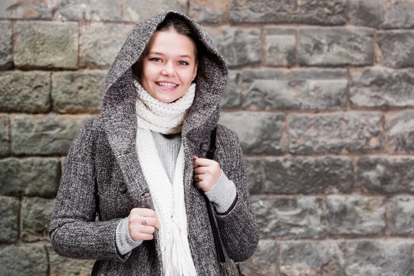 Femmina allegra nel cappuccio cappotto vicino alla parete — Foto Stock