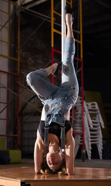 Sexy jovem mulher em jeans rasgado praticando pole dancing — Fotografia de Stock