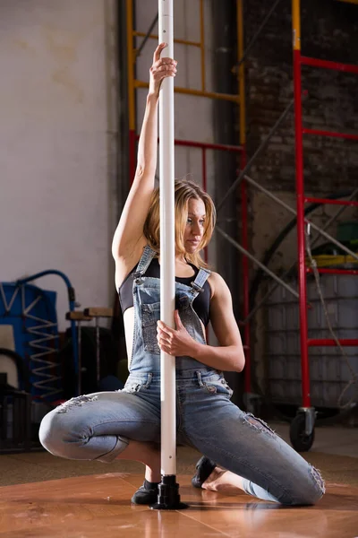 Jovem mulher em jeans rasgado realizando pole dance — Fotografia de Stock