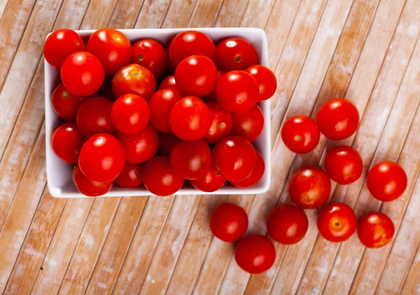 Спелые помидоры черри в белой тарелке на деревянном столе — стоковое фото