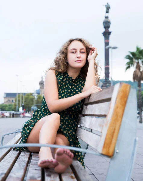 Atraktivní dívka turista sedí na dřevěné lavičce a přemýšlí v centru — Stock fotografie