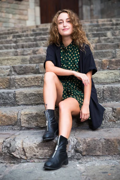 Ung kvinna turist i klänning sitter vid sten trappa och lekfullt poserar — Stockfoto