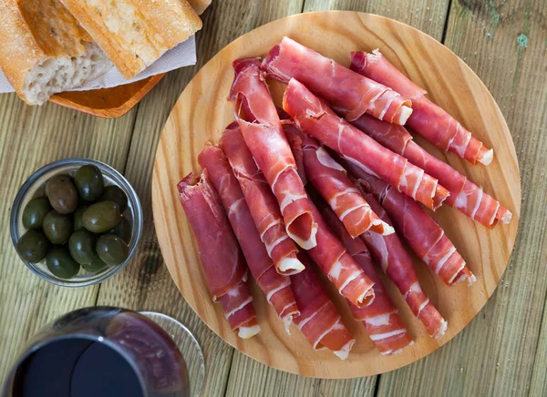 Spanish tapas - rolls of jamon serrano served on wooden board — Stock Photo, Image