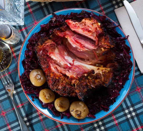 Gebackene Schweinshaxe mit Rotkohl und gebackenen Zwiebeln auf Teller serviert — Stockfoto