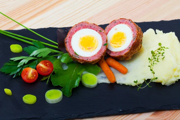 Dishes of traditional Scottish cuisine of scotch egg served with greens and potatoes — Stock Photo, Image