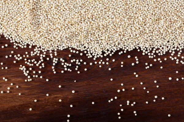 Heap of quinoa seeds scattered on wooden surface — Stock Photo, Image