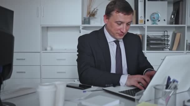 Zaměřený podnikatel pracuje sám s notebookem a papíry v kanceláři — Stock video