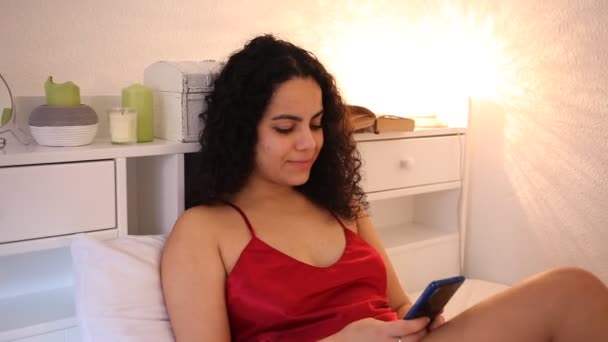 Sexy mladá dívka v červené spodní prádlo s mobilním telefonem na posteli — Stock video