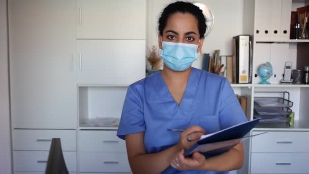 Retrato de mujer confiada médico en mascarilla que explica la prescripción al paciente en el consultorio en el hospital — Vídeos de Stock