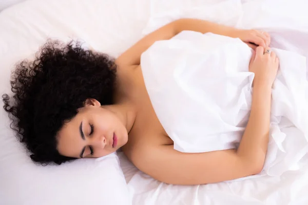 Chica durmiendo en sábanas blancas en la cama — Foto de Stock