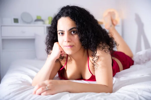 Aantrekkelijk jong meisje in rood lingerie poseren op bed — Stockfoto