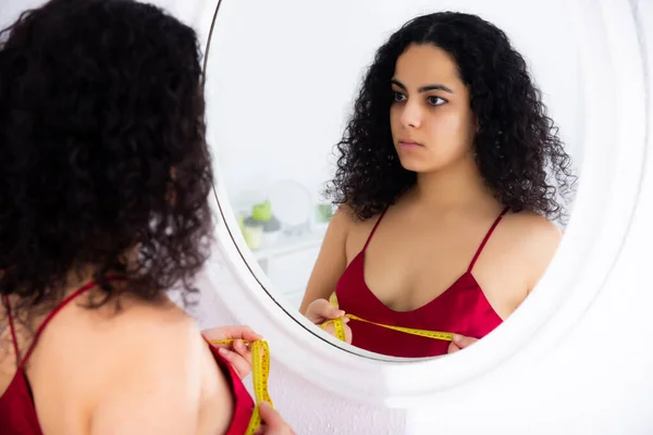 Dziewczyna mierzy piersi z centymetr patrząc na odbicie w lustrze — Zdjęcie stockowe