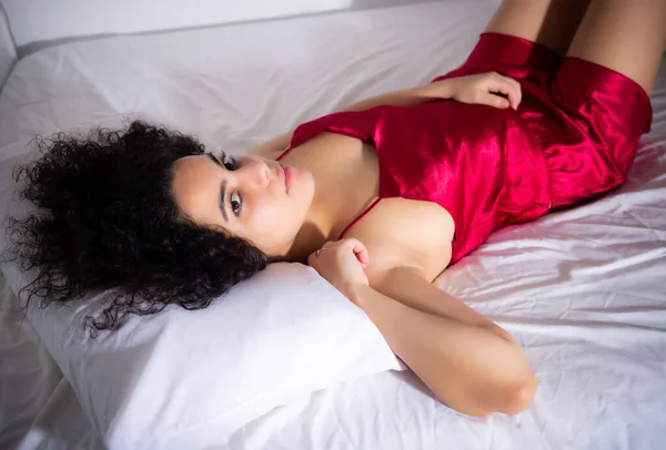 Retrato de mulher morena em lingerie vermelha gostando de deitar na cama — Fotografia de Stock