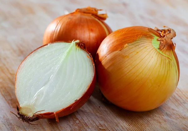 Imagen de bulbos de cebolla cortados sobre fondo de madera — Foto de Stock