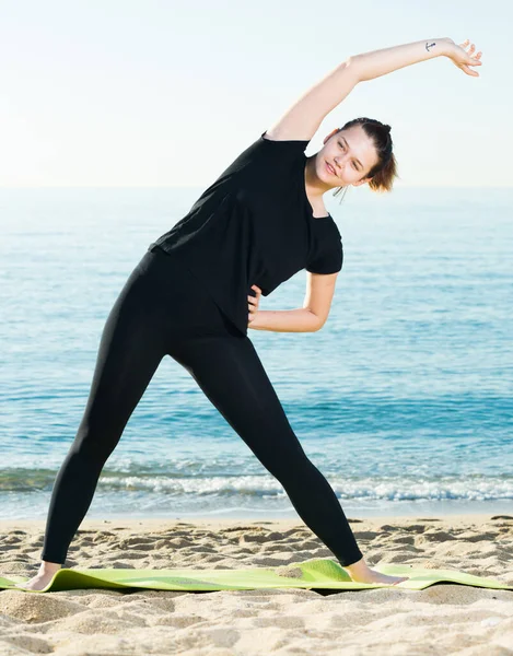 Siyah tişörtlü gülümseyen yetişkin kadın esneme egzersizi yapıyor. — Stok fotoğraf