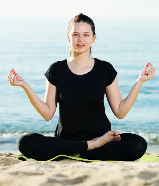 Kvinna i svart T-shirt sitter och övar meditation — Stockfoto