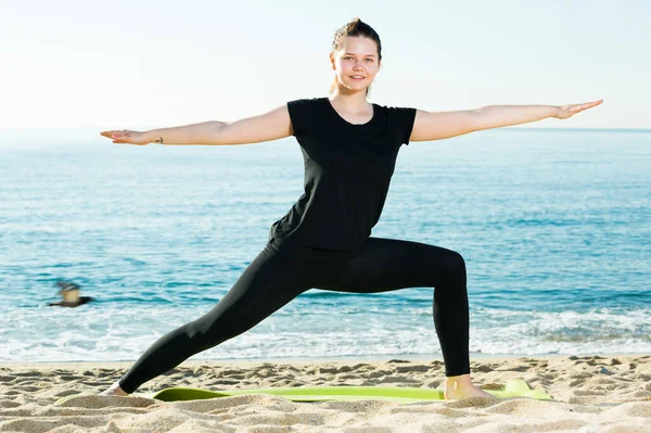 Dospělá žena v černém tričku cvičí jógu — Stock fotografie