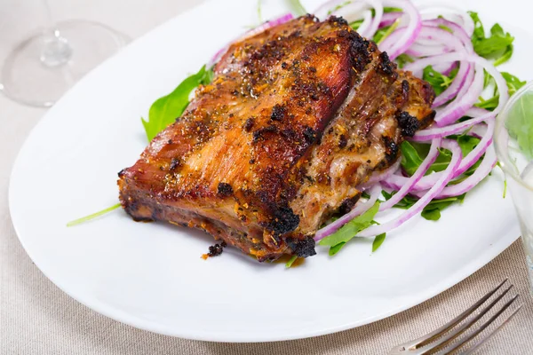 Tasty pork ribs baked under sauce, served with arugula and onion salad — Stock Photo, Image