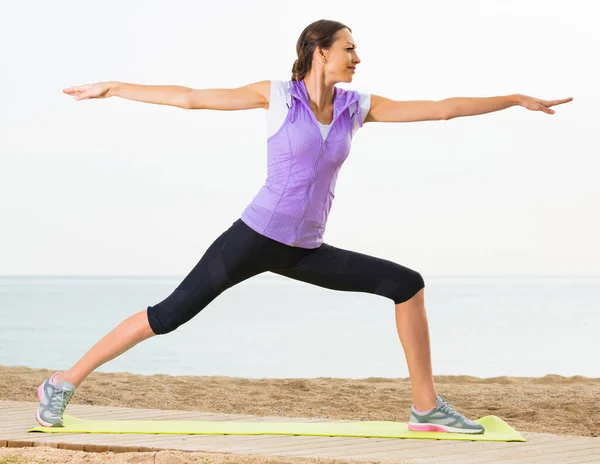 Hermosa mujer haciendo ejercicio de yoga posa en la playa —  Fotos de Stock