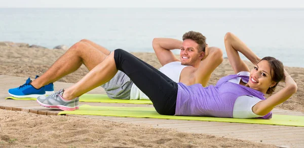 Młoda kobieta i facet trening na plaży nad oceanem — Zdjęcie stockowe