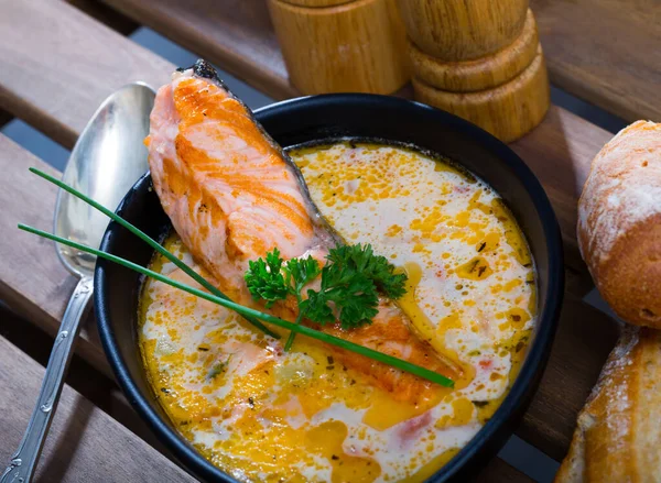 Köstliche Rahmsuppe mit Lachs und Gemüse, serviert in einer Schüssel mit Brot am Tisch — Stockfoto