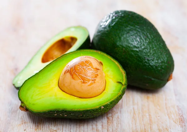 Close-up van gesneden avocado met bot aan houten tafel — Stockfoto