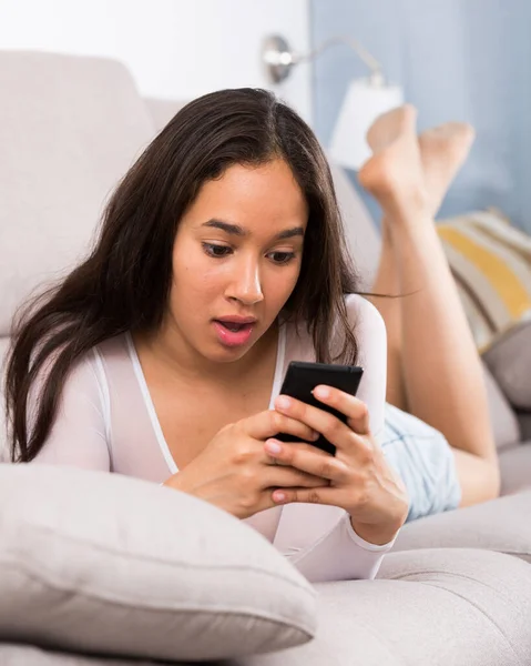 Young glad woman lying with mobile — Stock Photo, Image