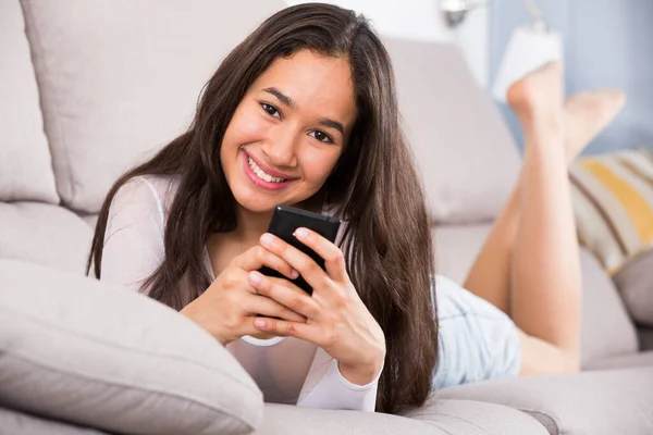 Smiling female with mobile phone on sofa — Stock Photo, Image