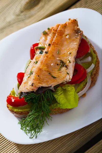 Вкусный сэндвич с форелью, гуакамоле и свежим красным перцем на тарелке — стоковое фото