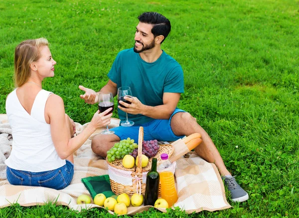 Pareja están hablando y bebiendo vino en tiempo de picnic al aire libre —  Fotos de Stock