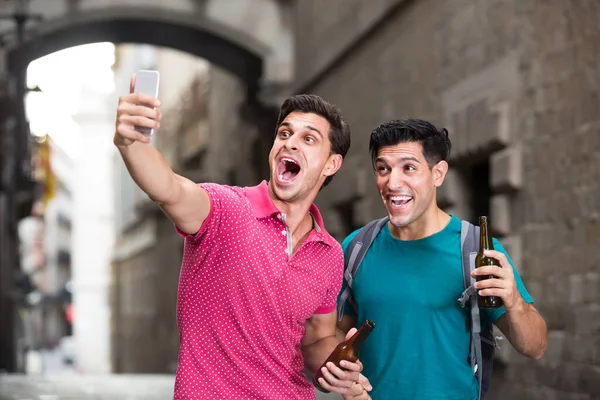 Jonge mannelijke fans wandelen met bier en maken selfie in de buurt van bezienswaardigheden in Barcelona — Stockfoto