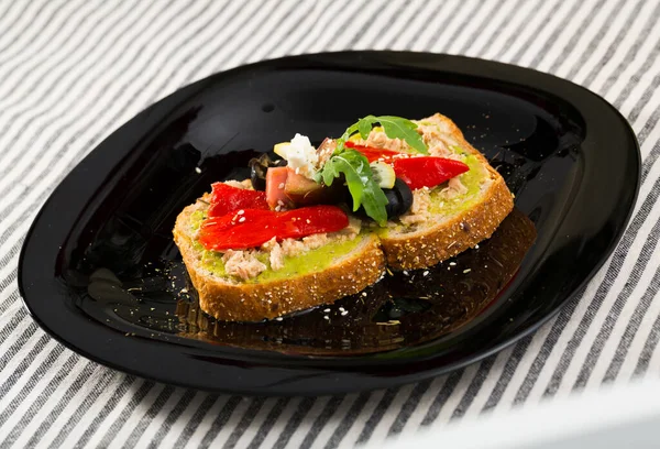 Sanduíche com guacamole, atum enlatado, feta, legumes em prato preto — Fotografia de Stock