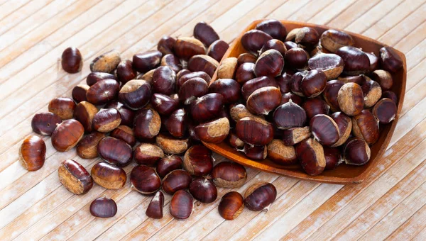 Castagne dolci commestibili non pelate su sfondo di legno — Foto Stock