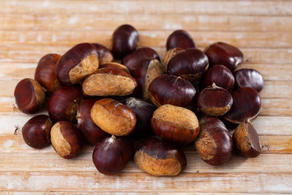 Pilha de castanhas comestíveis em bruto na superfície de madeira — Fotografia de Stock