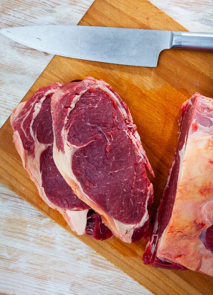 Lombo de vaca cru com pedaços cortados na mesa de madeira — Fotografia de Stock