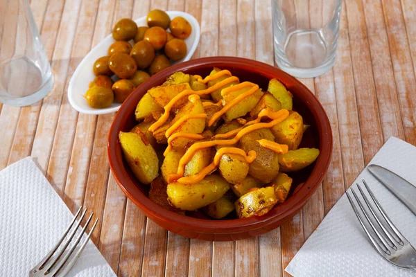 Gotowe patatas bravas z sosem serwowane na talerzu na drewnianym stole — Zdjęcie stockowe