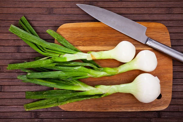 Whole green young onion bulbs on wooden desk — Stock Photo, Image