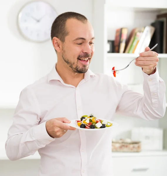 Smiling man looking at greek salad — Stock Photo, Image