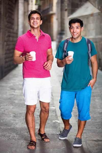 Gli amici uomini stanno bevendo caffè nel tempo passeggiando in città. — Foto Stock