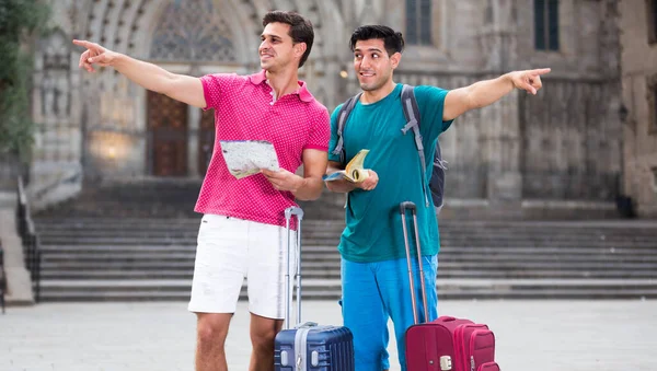 Due amici turisti con valigie stanno camminando con mappa e gui — Foto Stock