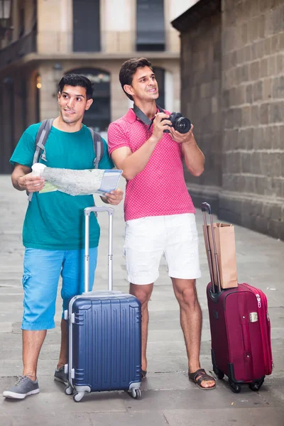 Uomini gioiosi stanno camminando con la fotocamera e cercando la strada per la vista storica nella mappa di Barcellona — Foto Stock