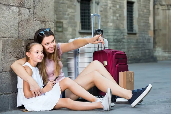 Ung mor med sin dotter vilar nära gamla väggen under resan pekar på något — Stockfoto