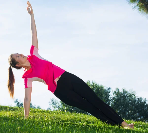 Smiling girl in pink T-shirt is practicing yoga — Stock Photo, Image