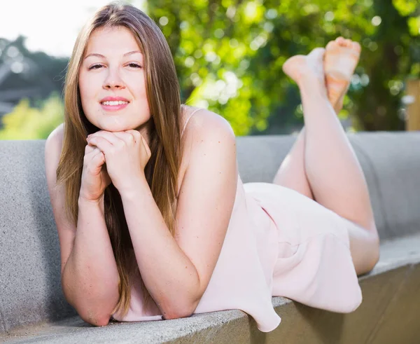 Веселая молодая девушка позирует на скамейке в свободное время — стоковое фото