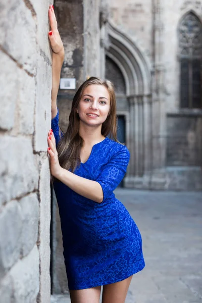 Fröhliches Weibchen posiert verspielt im blauen Kleid an der Wand — Stockfoto